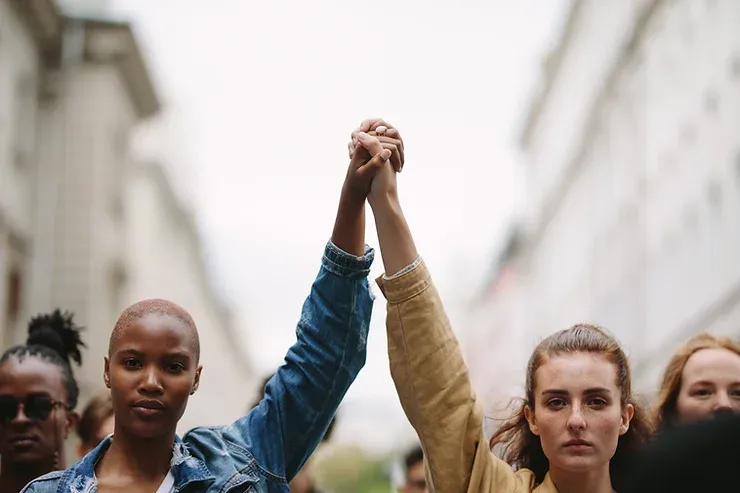 Deux femmes se tenant la main dans une foule.