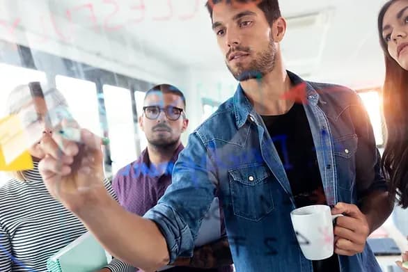 Un homme qui ecrit sur le tableau avec ses collegues 